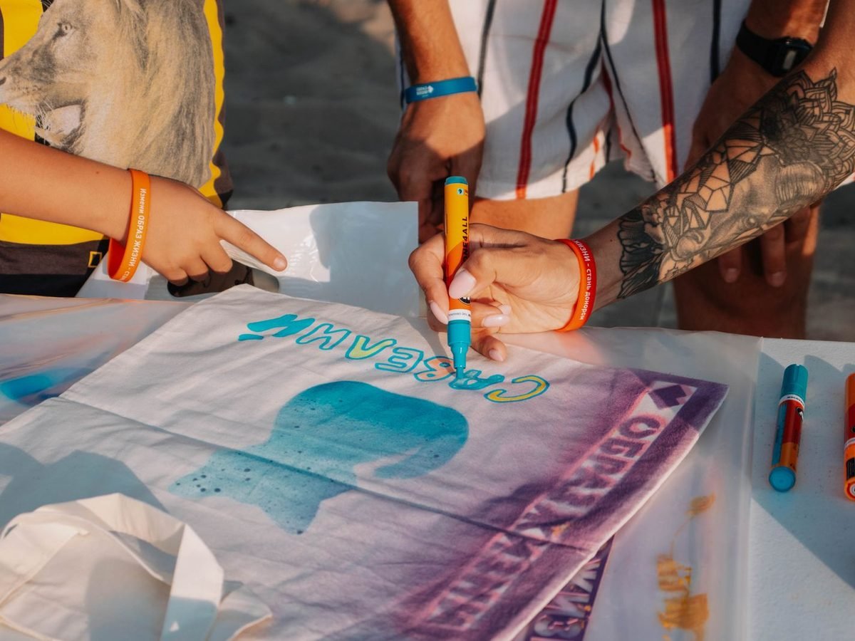 Manos decorando una camiseta en un taller al aire libre